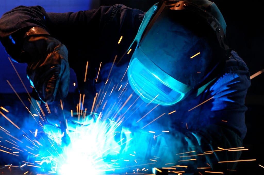 A person welding while wearing safety equipment.